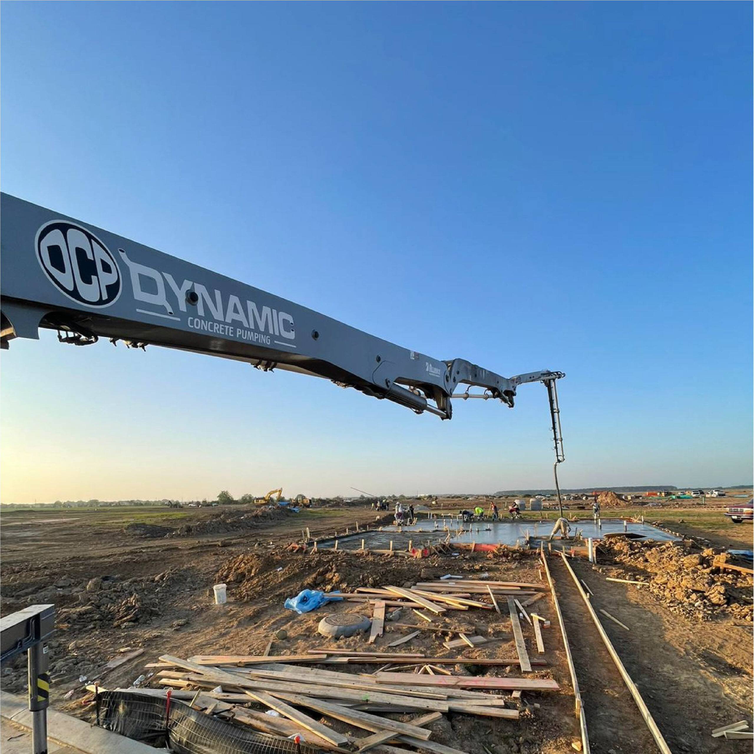 Dynamic Concrete Pumping boom branding placing a foundation at sunset